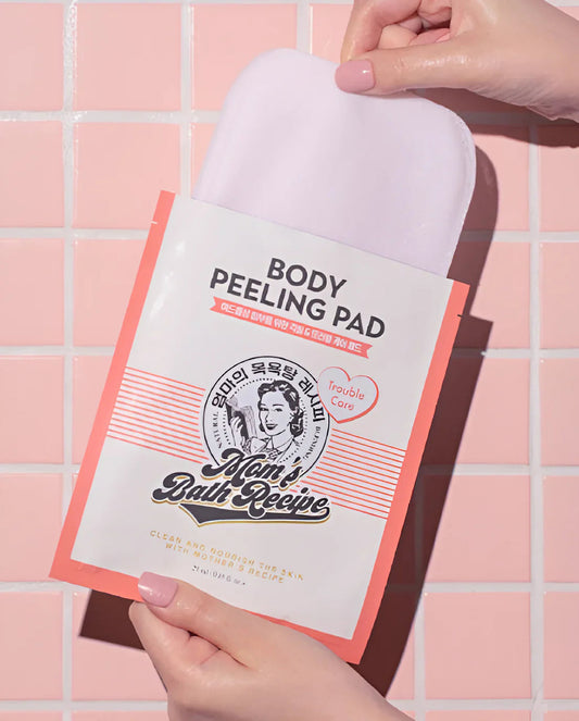 Body peeling pad with 'Mom's Bath Recipe' packaging held by a hand against a tiled wall background.