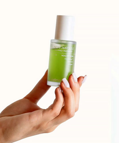 Hand holding a green skincare bottle with a white cap on a white background