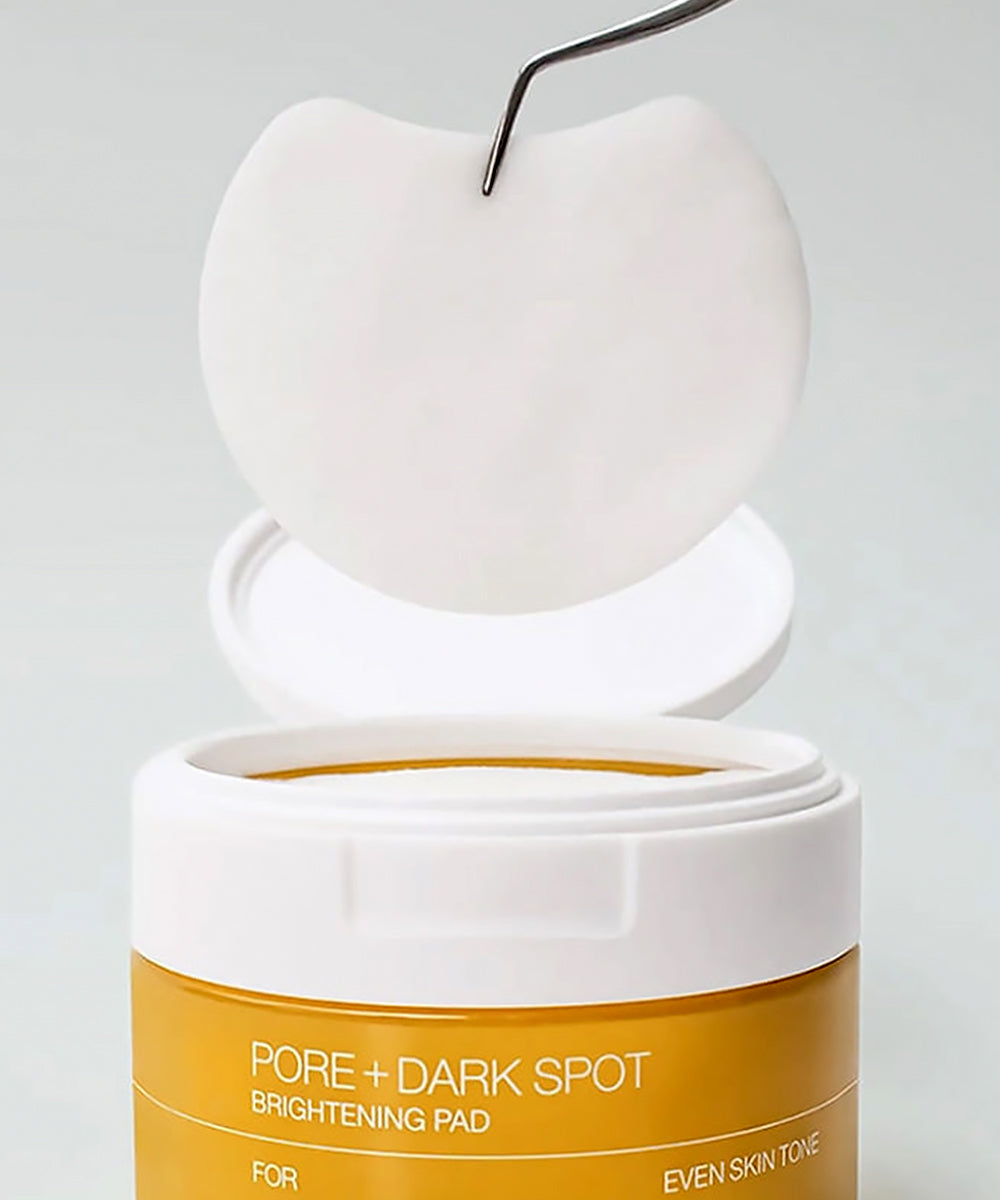Pore and dark spot brightening pad container with applicator on a gray background