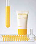 Cosmetic tube with yellow liquid and a bottle cap on a light gray background