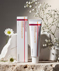 Madeca Cream tube and packaging on a stone surface with white flowers