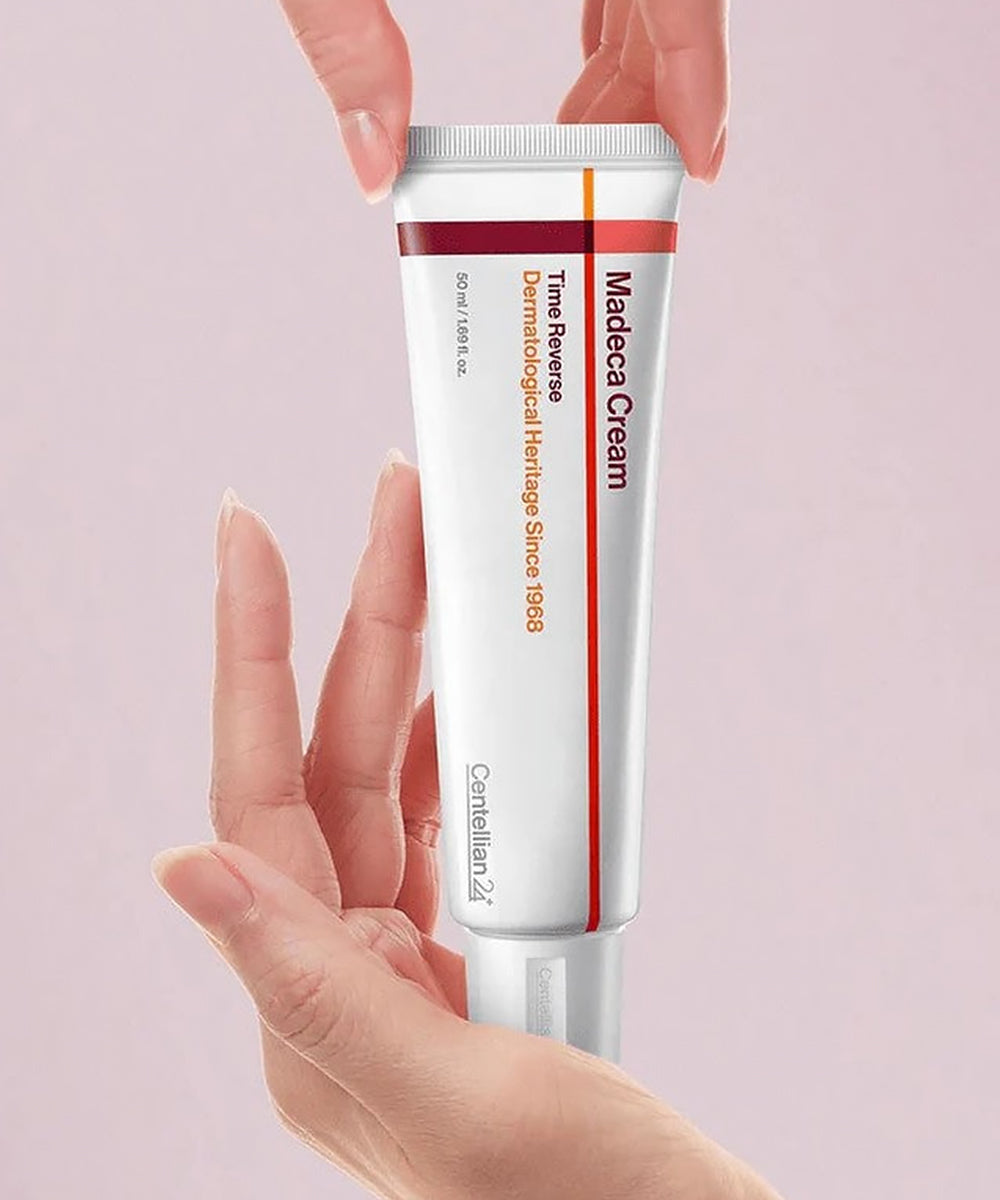 Tube of Madeca Cream held by a hand against a light pink background
