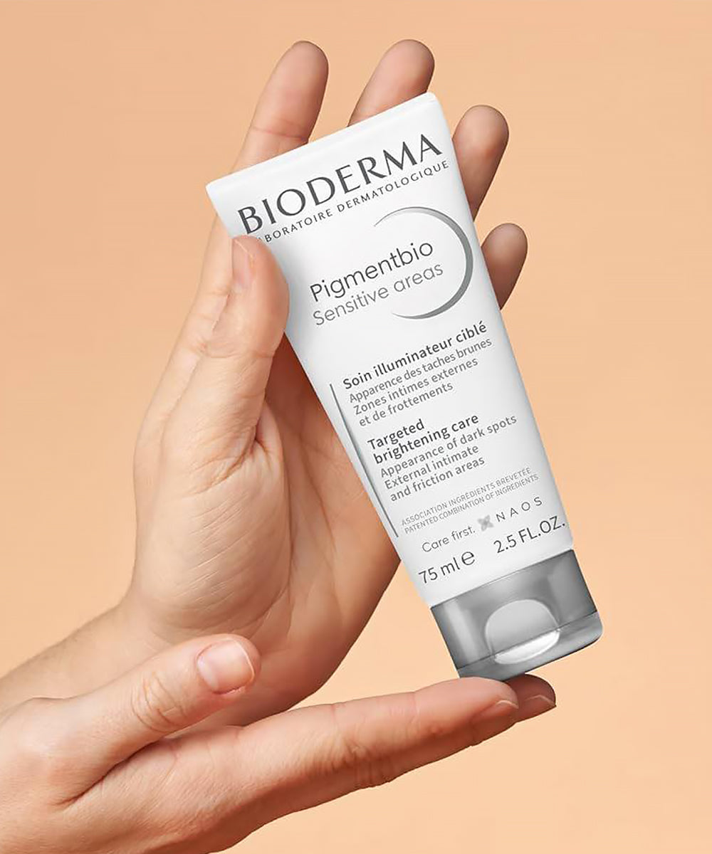 Hand holding a Bioderma skincare product against a beige background