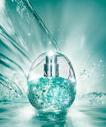 A clear spherical perfume bottle filled with sparkling aqua liquid and silver atomizer, set against a water-splashed teal background. The bottle has the brand name 'anua' printed on the front.