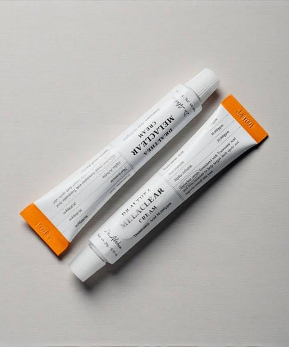 Top-down view of the Dr.Althea Melaclear Cream tube lying next to a decorative swirl of the cream to showcase the product consistency