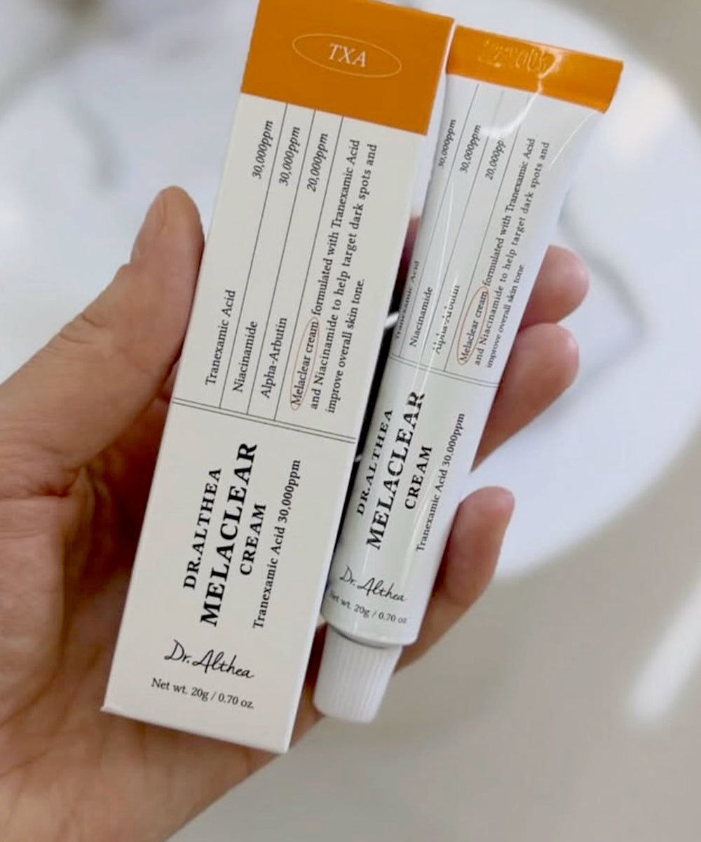 A person's hand holding the Dr. Althea Melaclear Cream tube, showcasing the sleek, travel-friendly packaging and compact size