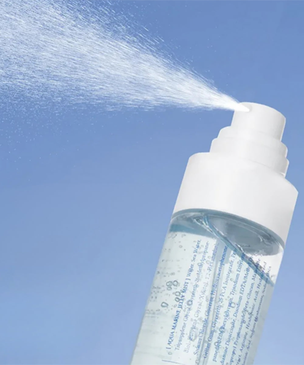 Spray bottle with liquid being sprayed against a clear blue sky
