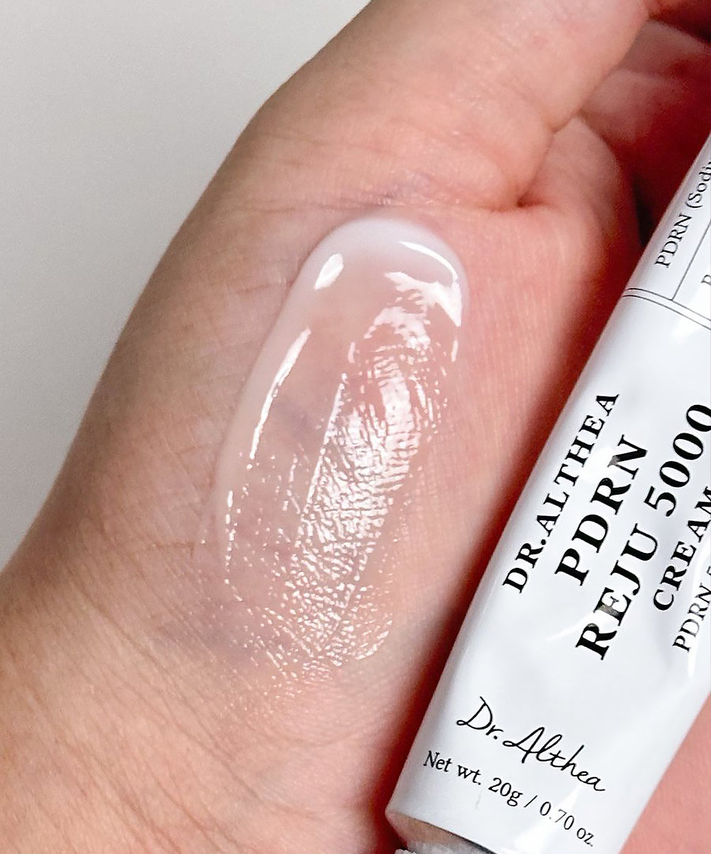 Hand applying Dr. Althea PDRN 5000 cream to a finger with a white background