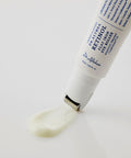 Macro shot showing the smooth, creamy texture of the Dr. Althea Retinol treatment being dispensed through the "flat iron" metal applicator on a reflective white surface
