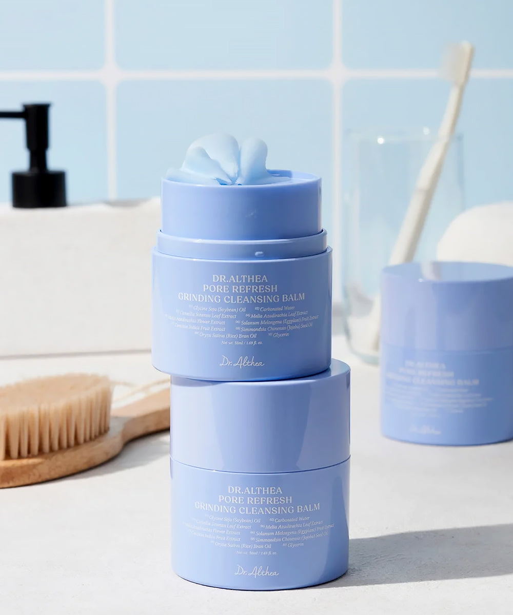 Two blue skincare products stacked on a bathroom counter with a light blue tiled wall in the background.