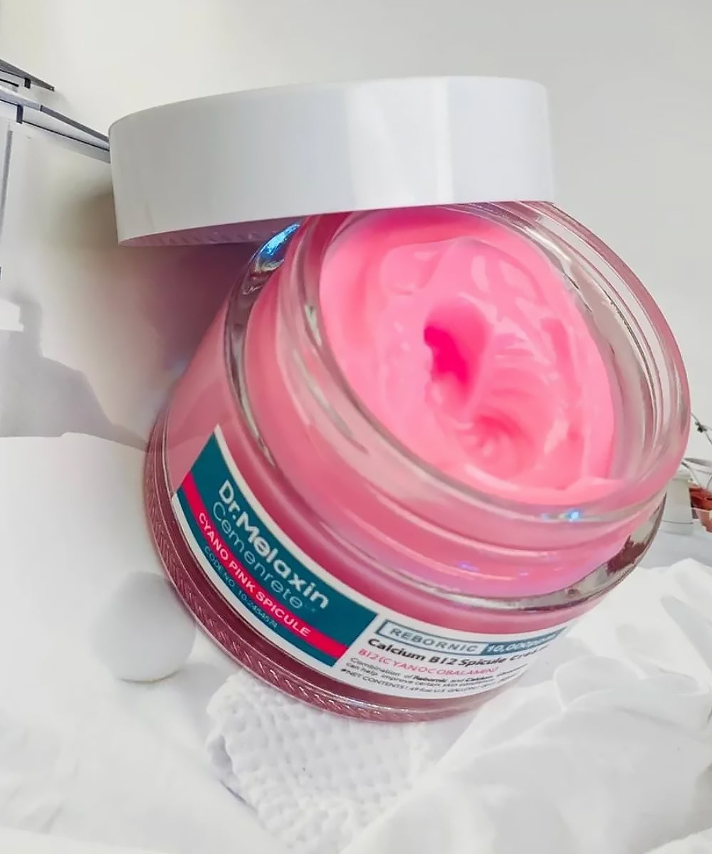 Detailed view of the Dr. Melaxin Calcium B12 Spicule Cream tube and packaging box, emphasizing the "Skin-Repair & Strengthening" claims and the signature pink color palette