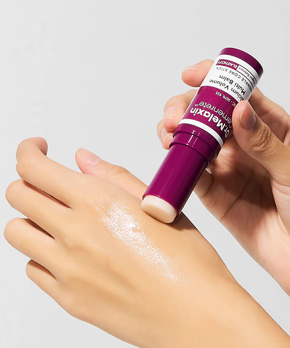 A lifestyle demonstration showing the Dr. Melaxin Calcium Volume Multi Balm being applied to the back of a hand, revealing a glossy, hydrating, and smooth texture on the skin