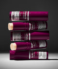 An artistic horizontal stack of five Dr. Melaxin Cemenrete Calcium Volume Multi Balm tubes, showcasing both the sleek plum packaging and the solid balm core