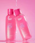 Two pink bottles of Eqqual Berry skincare products on a pink background