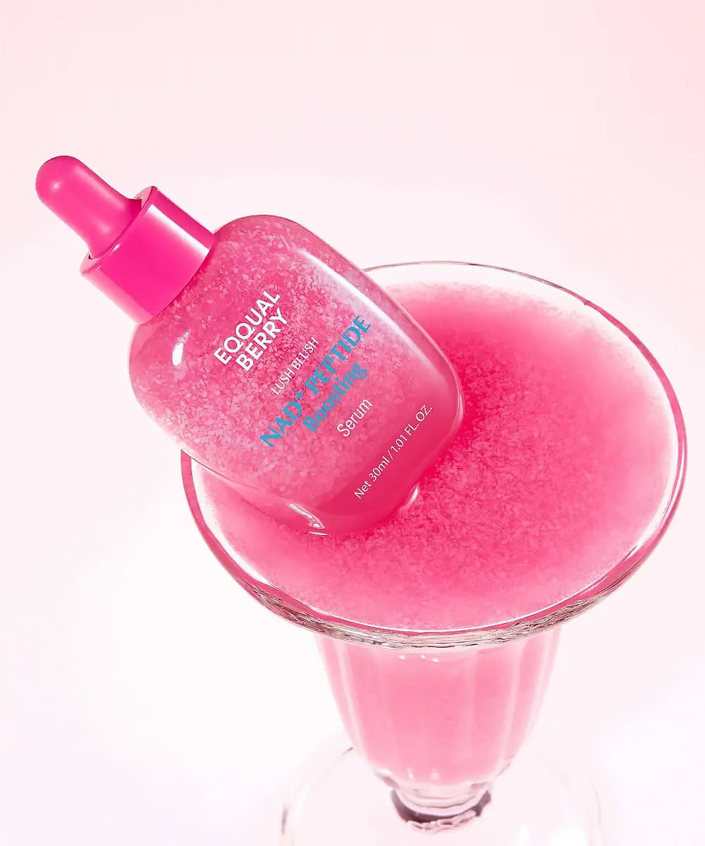 Pink serum bottle with dropper over a glass filled with pink liquid on a white background
