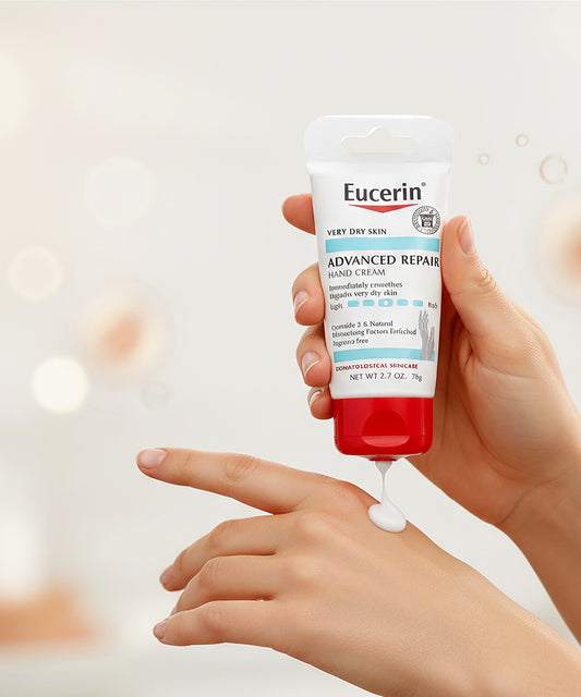 Hand applying Eucerin Advanced Repair Hand Cream to another hand against a blurred background