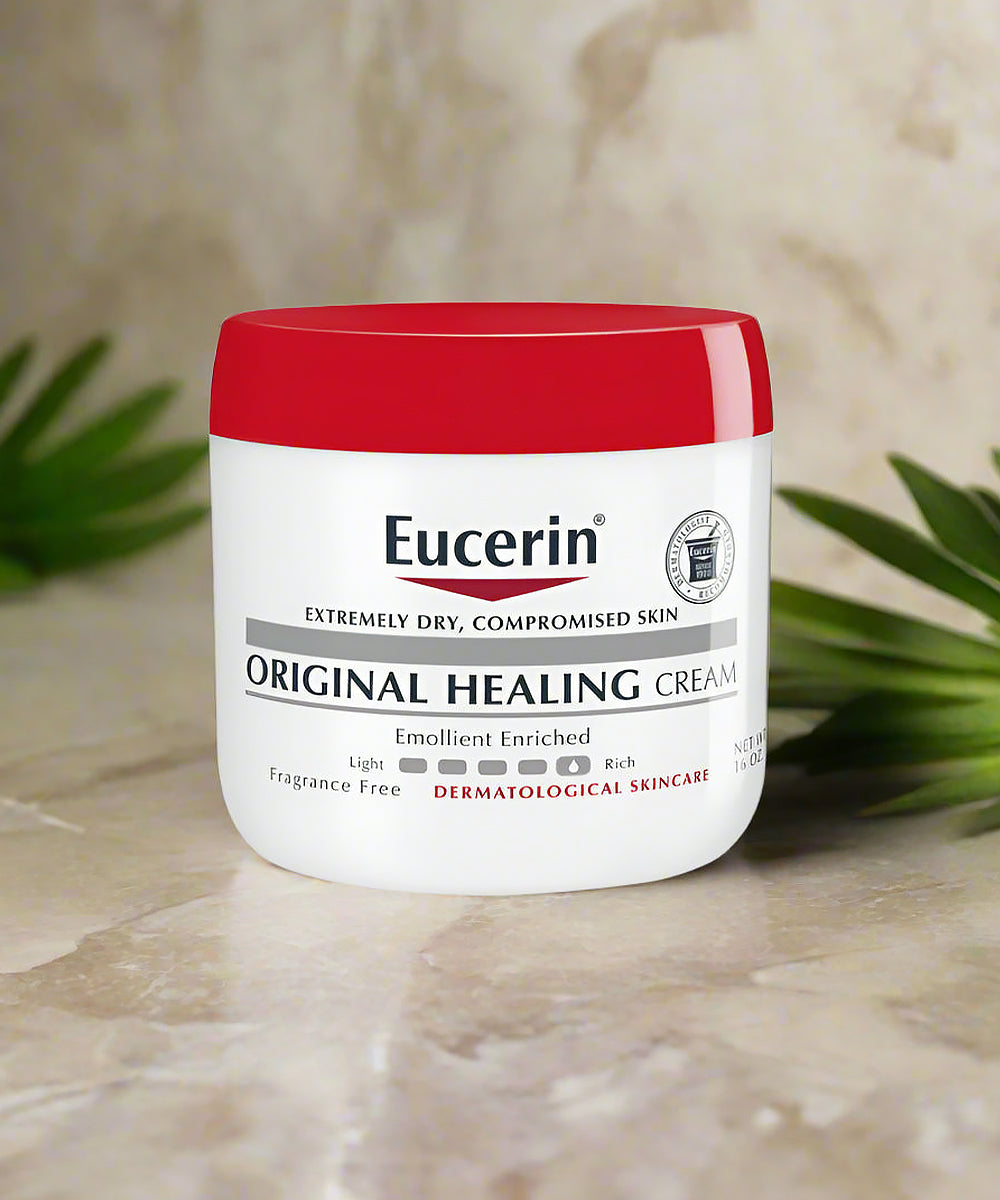 Eucerin Original Healing Cream jar on a marble surface with green leaves in the background