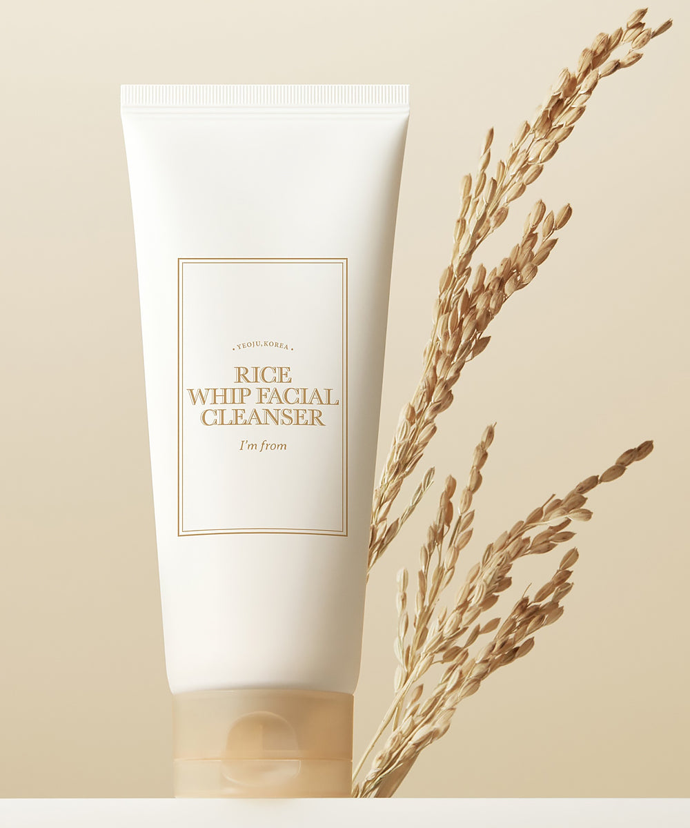 Tube of Rice Whip Facial Cleanser with dried grass on a beige background