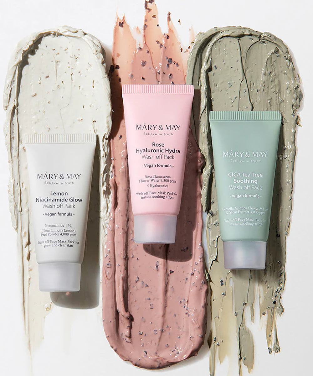 Texture showcase of Mary & May wash-off masks with tubes of Lemon Niacinamide, Rose Hyaluronic, and Cica Tea Tree placed over thick, creamy swatches of their respective formulas