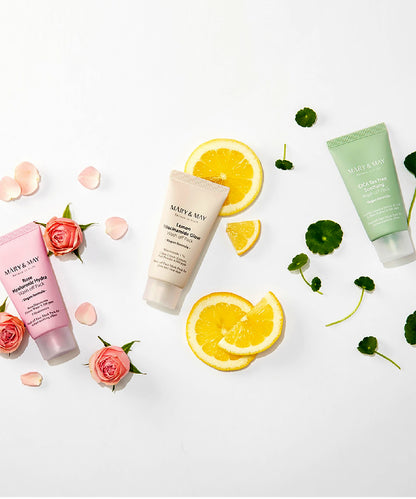 Lifestyle flat lay of Mary & May vegan masks on a white surface, surrounded by fresh rosebuds, lemon slices, and cica leaves to emphasize the natural, plant-based ingredients