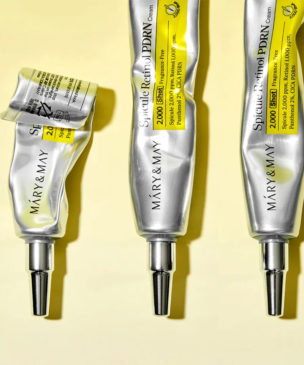 An aesthetic lifestyle shot of the Bioderma Sébium Kerato+ tube lying on a white surface next to a textured smear of the cream and fresh water droplets