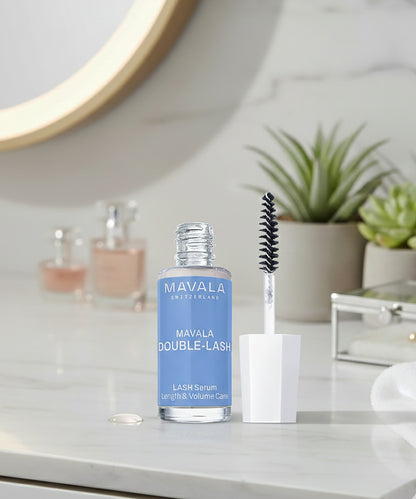 Mavala Double-Lash lash serum with applicator on a bathroom counter.