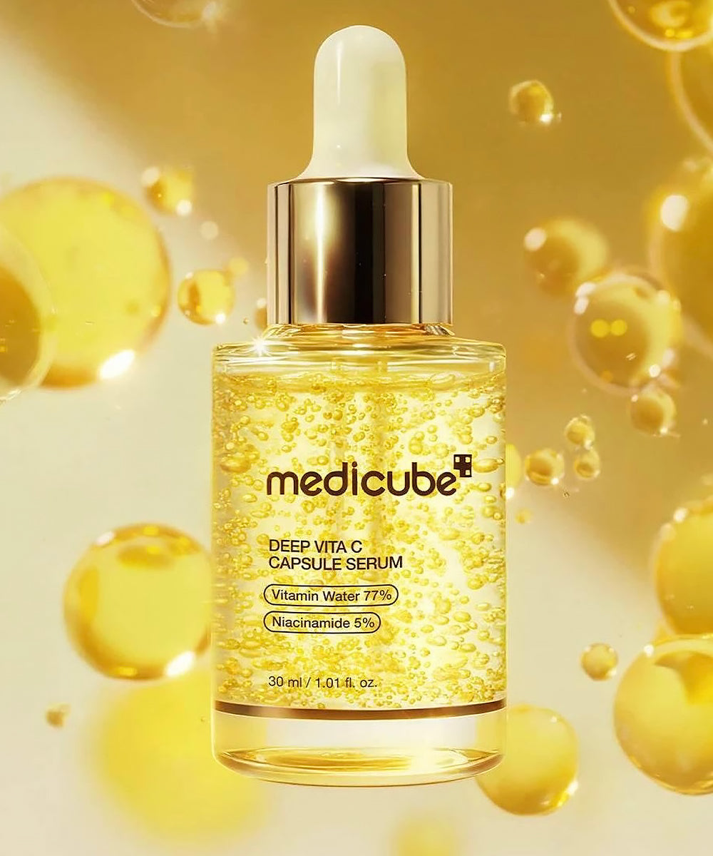 Extreme close-up of The Medicube Deep Vita C Serum bottle, visually highlighting the signature formulation of yellow capsules suspended in the clear serum