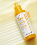 Close-up of a glass dropper dispensing the vibrant yellow Kojic Acid and Turmeric peeling serum, highlighting its lightweight and concentrated liquid formula