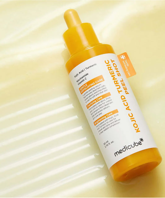 Close-up of a glass dropper dispensing the vibrant yellow Kojic Acid and Turmeric peeling serum, highlighting its lightweight and concentrated liquid formula