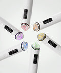 Six handheld beauty devices arranged in a circular pattern on a clean white background. Each device has a white body, a black digital display screen, and a metallic trim accent in different colors: pink, gold, purple, blue, green, and silver.