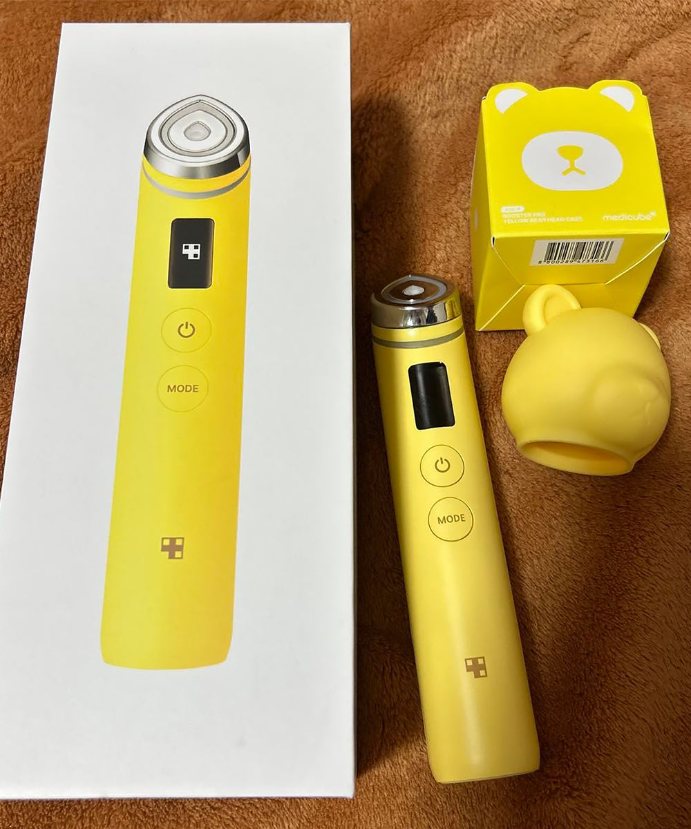 A person holding the Medicube Age-R Booster Pro against their cheek, demonstrating the 6-in-1 facial device in use to achieve a radiant, "glass skin" complexion at home