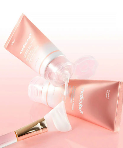 Medicube skincare products including a tube, brush, and applicator on a pink background