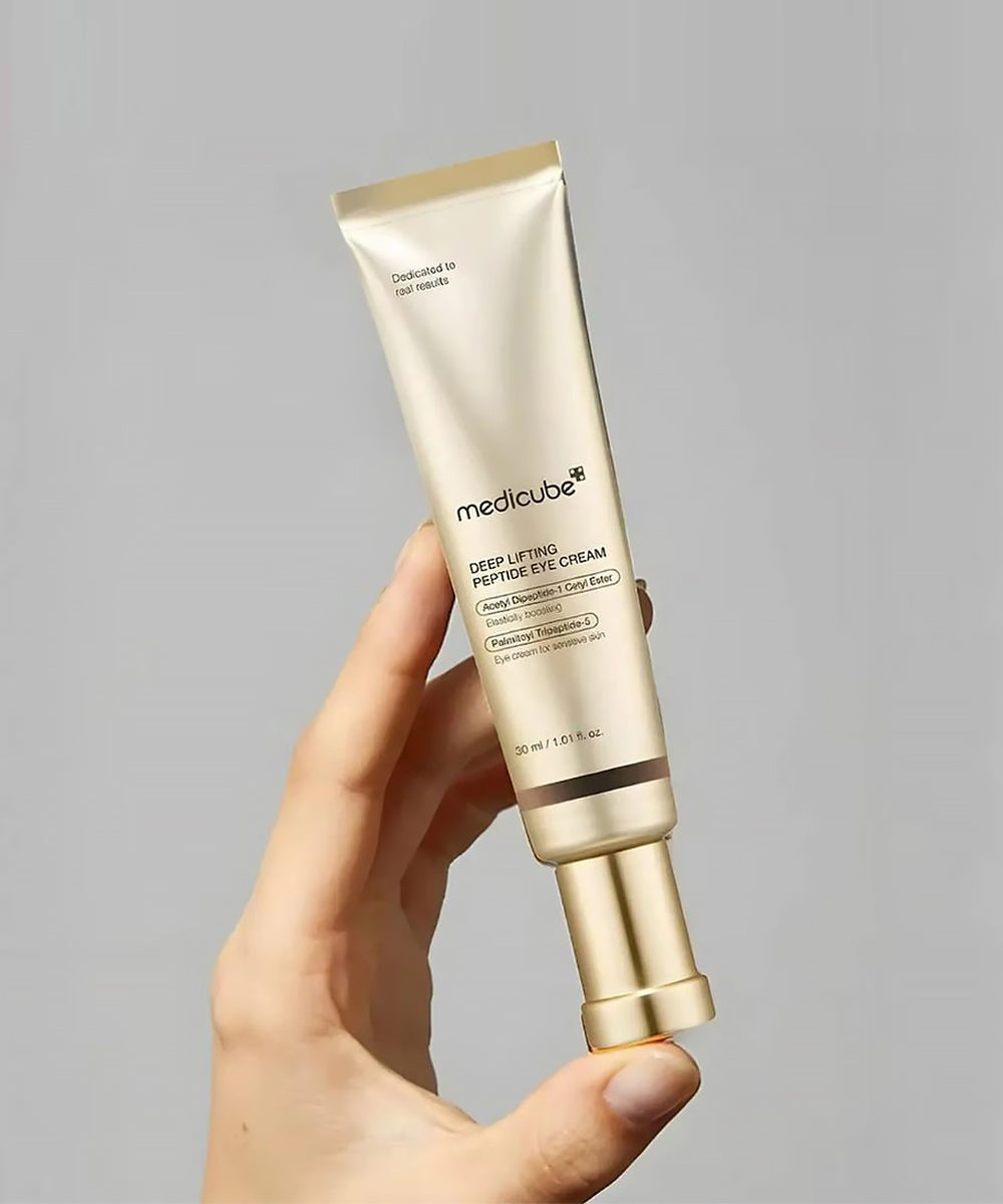 Hand holding a Medicube skincare product against a gray background