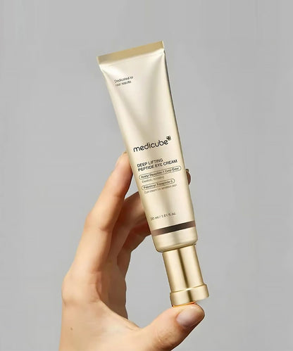 Hand holding a Medicube skincare product against a gray background