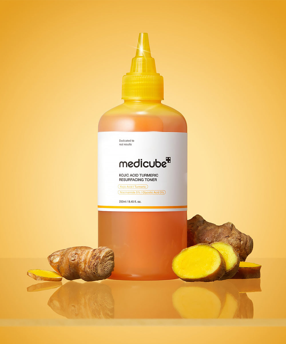 Bottle of Medicube toner with turmeric roots and slices on a yellow background