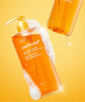 Orange bottle of Medicube body wash with pump on a yellow background