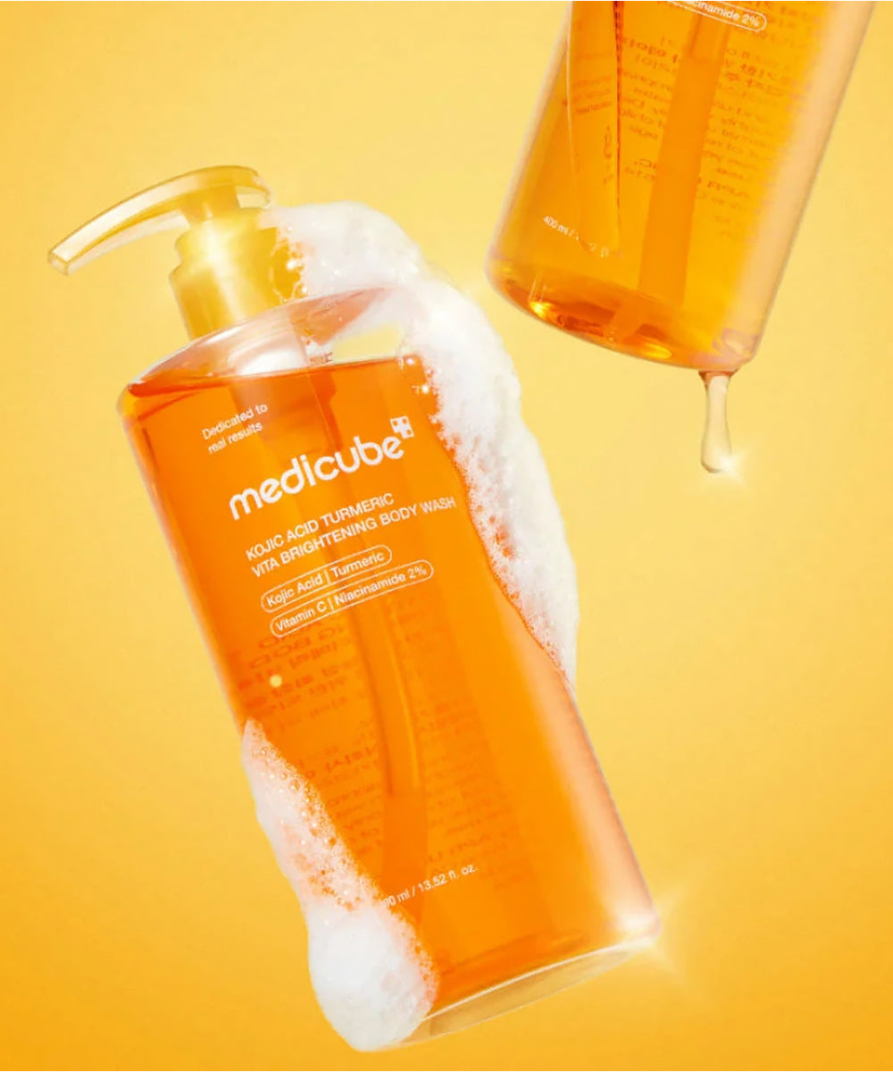 Orange bottle of Medicube body wash with pump on a yellow background