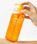 Orange bottle of Medicube skincare product being held with a white background