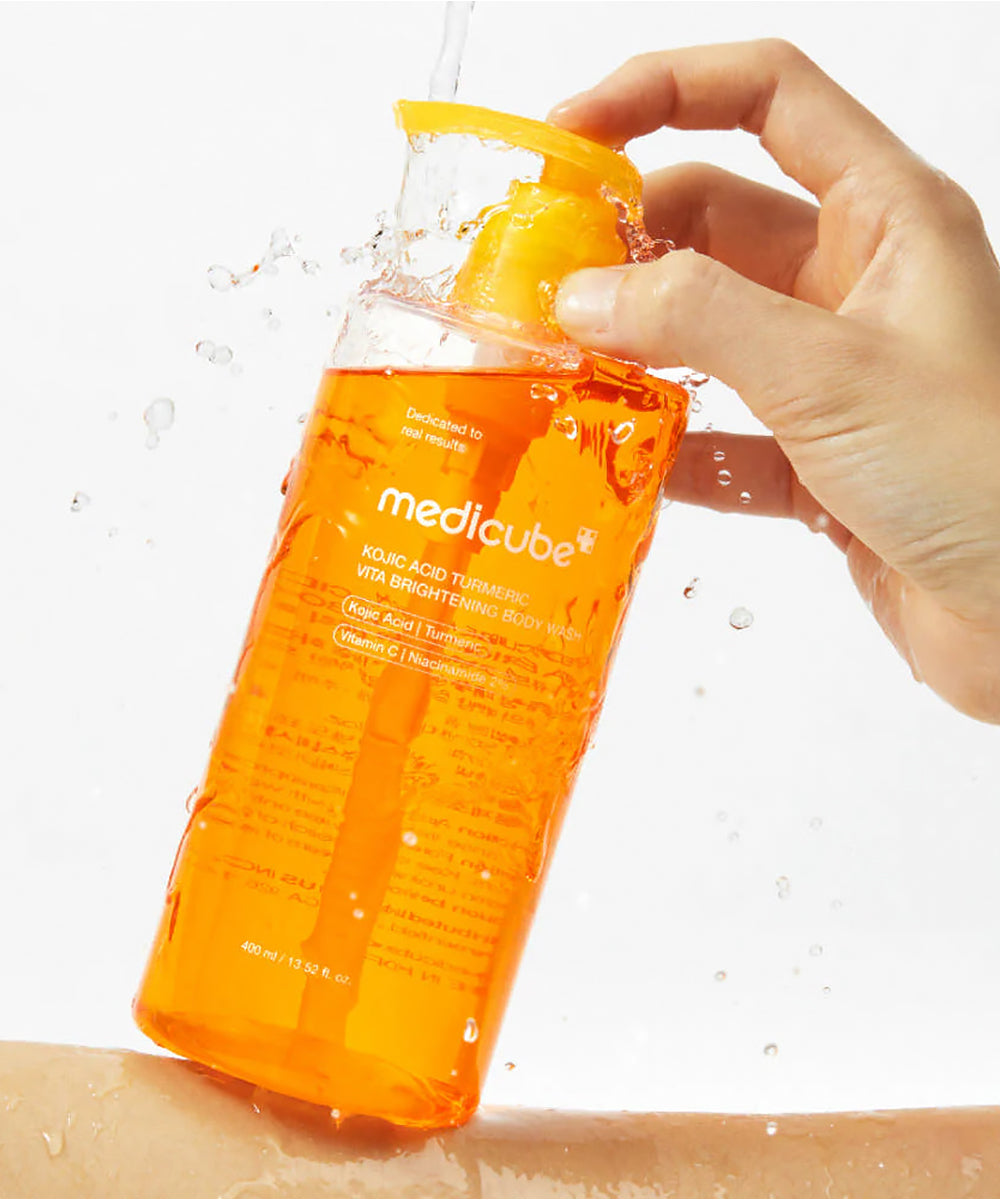 Orange bottle of Medicube skincare product being held with a white background