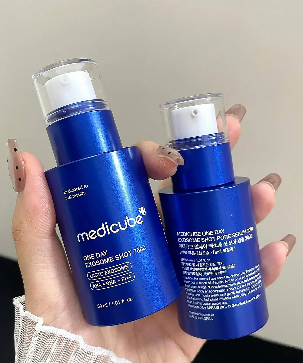 Two blue skincare bottles held in a hand against a neutral background
