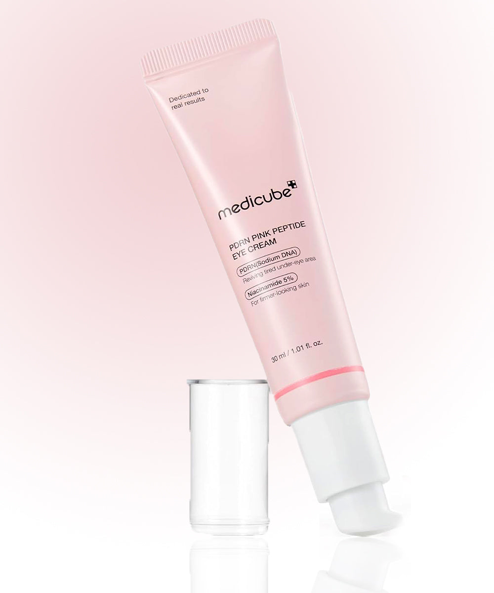 Pink eye cream tube with applicator on a light pink background