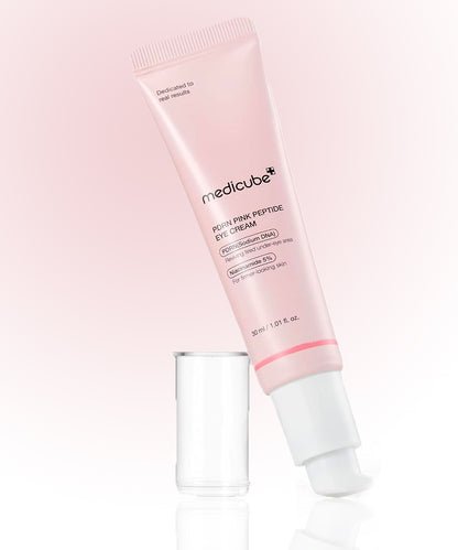 Pink eye cream tube with applicator on a light pink background