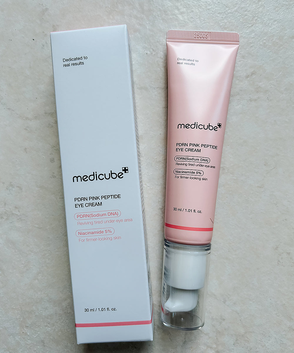 Medicube pink eye cream tube and packaging on a light gray surface