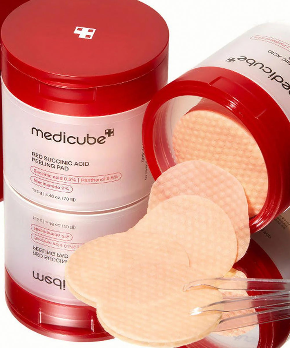 Medicube red succinic acid peeling pad container with peeling pads and a brush on a white background