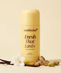 A bottle of medicube Fresh That Lasts deodorant in Vanilla & Pistachio, styled with vanilla beans, pistachios, and a white flower on a warm cream background.