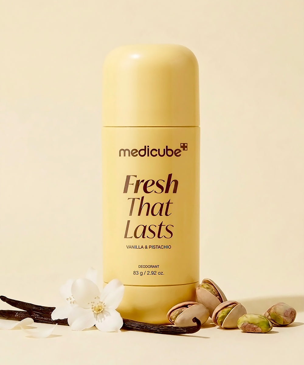 A bottle of medicube Fresh That Lasts deodorant in Vanilla & Pistachio, styled with vanilla beans, pistachios, and a white flower on a warm cream background.