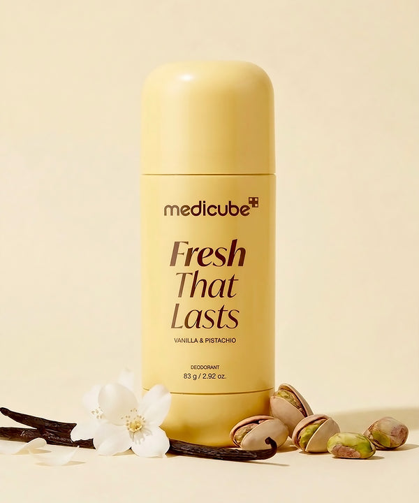 A bottle of medicube Fresh That Lasts deodorant in Vanilla & Pistachio, styled with vanilla beans, pistachios, and a white flower on a warm cream background.