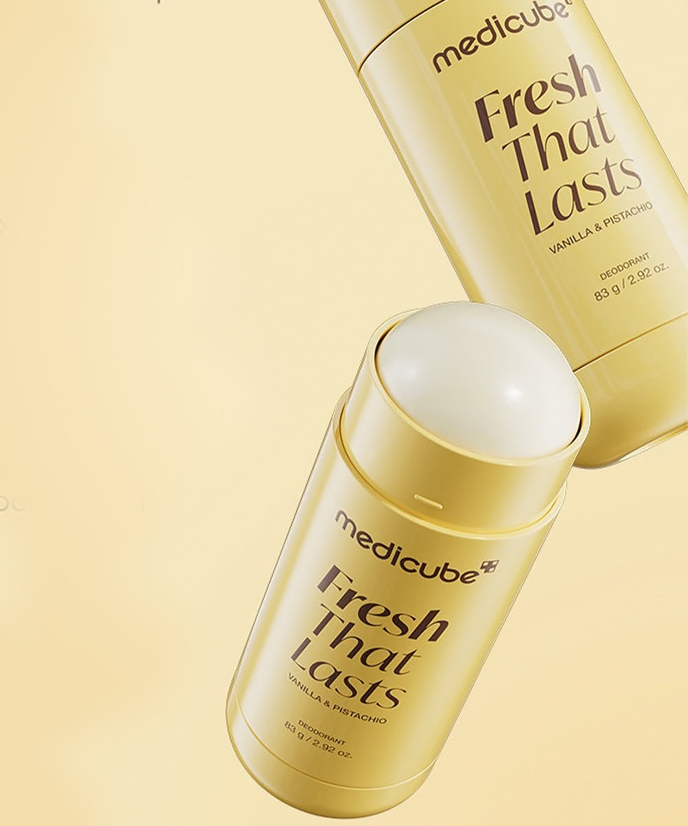 Two Medicube Fresh That Lasts deodorant sticks in a glossy gold packaging, with one upright and one horizontal, on a warm beige background.