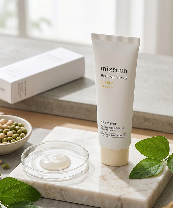 Tube of mixsoon Bean Sun Serum on a marble surface with green leaves and a bowl of beans.