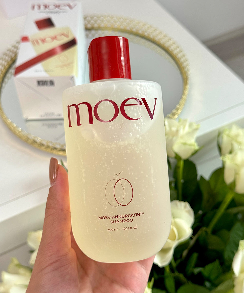 Hand holding a bottle of moev shampoo with a blurred background